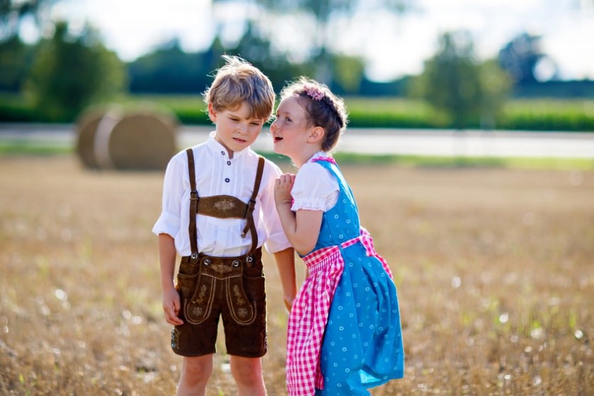 Two kids, boy and girl in traditional Bavarian costumes in wheat field